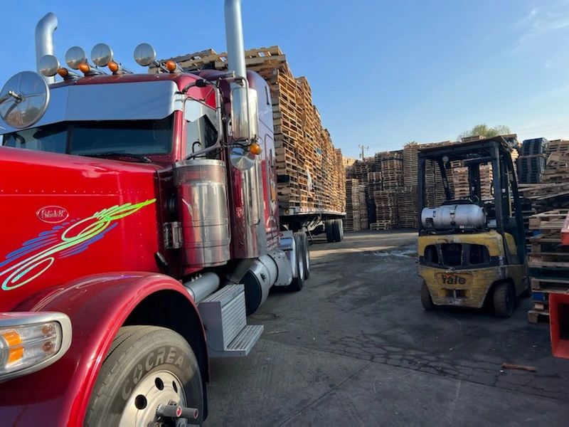 Red Peterbilt truck and forklift at pallet yard